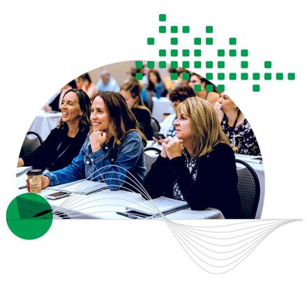 A group of three women smiling and having a conversation in a conference setting.